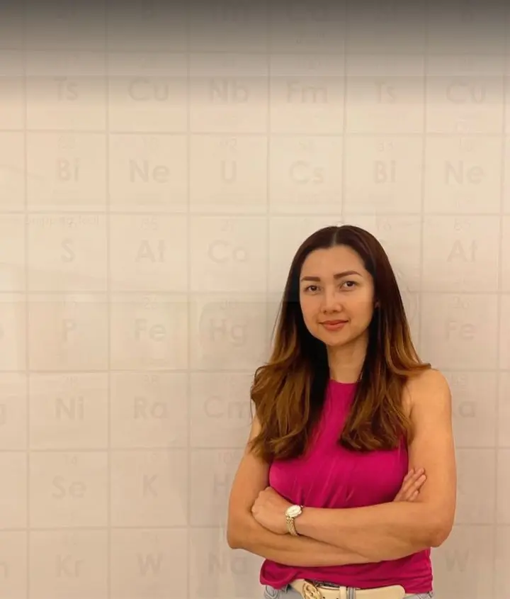 A woman in pink standing in front of a white wall.