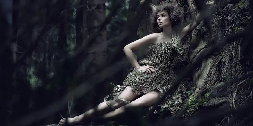 Woman in camouflaged dress in a forest.